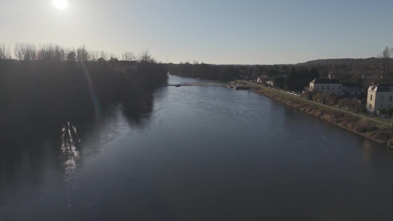 Et luftfoto svæver over den rolige Loire-flod, mens skumringen falder over en fjern landsby i Frankrig