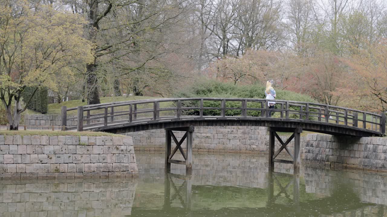 벨기에 하셀트의 일본 정원에서 나무 다리를 건너는 애니메이션 코스프레 의상을 입은 소녀