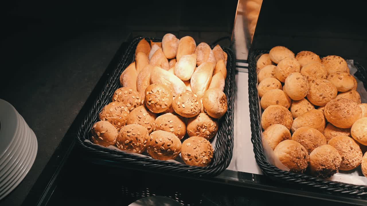 Different kinds of mini bread rolls are displayed in warm light