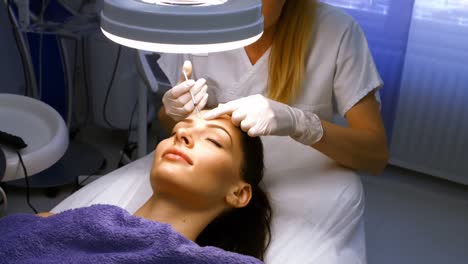 doctor inserting facial injection on female patient forehead