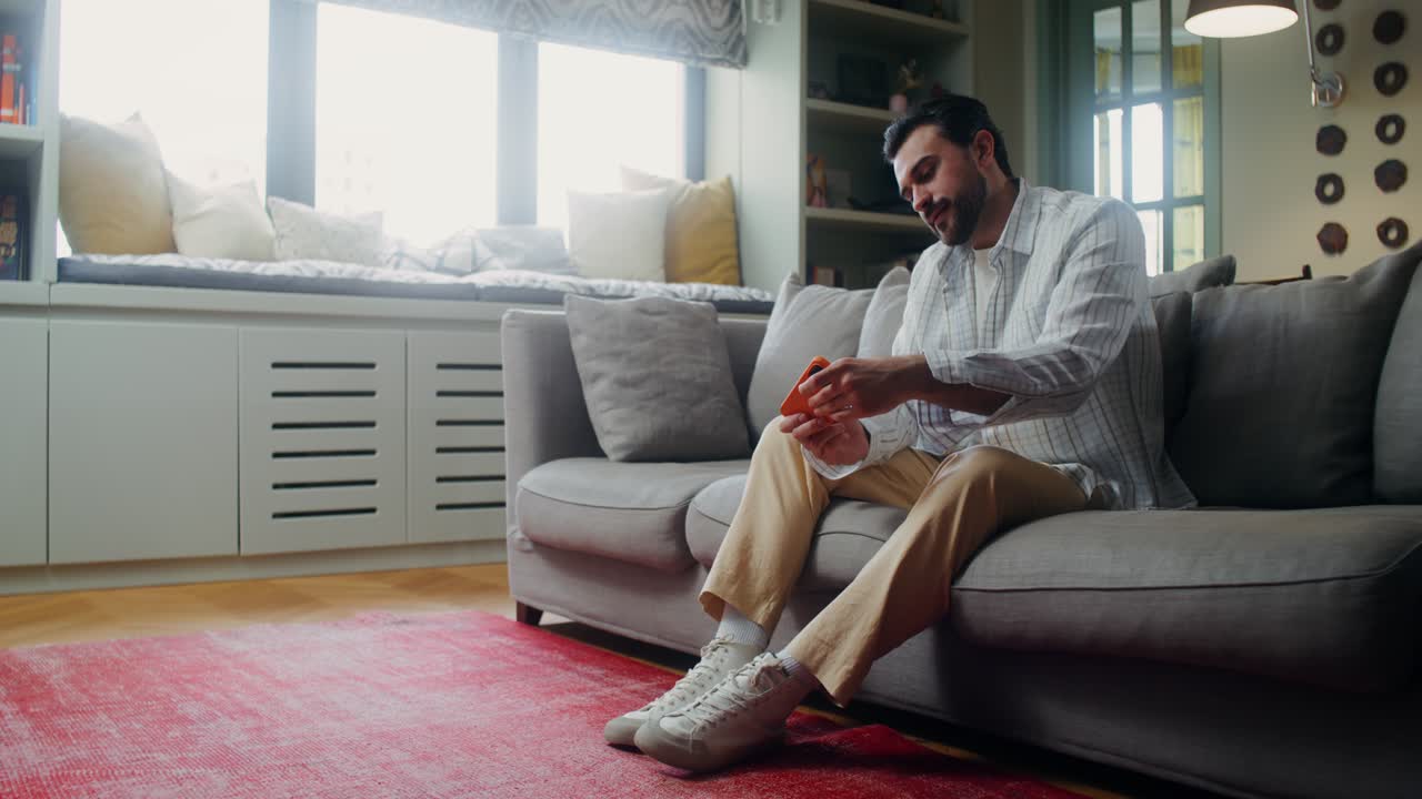 집에서 소파에서 전화를 사용하는 남자