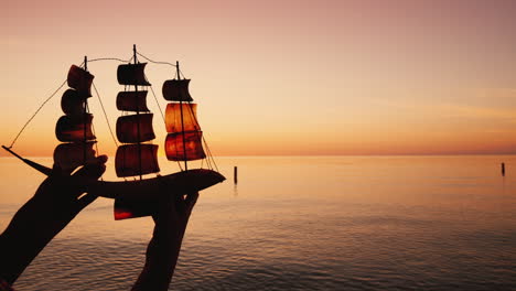 man holds a toy sailboat on a background of the sea travel and discovery concept