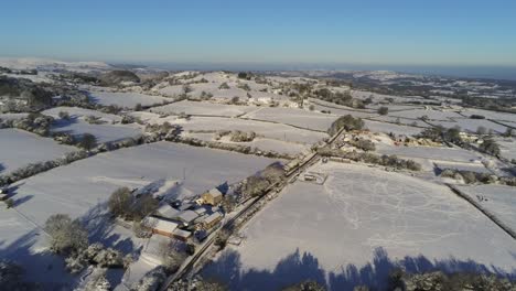 frío invierno nevado británico patchwork tierras de cultivo campo rural escena aérea al amanecer inclinándose hacia abajo