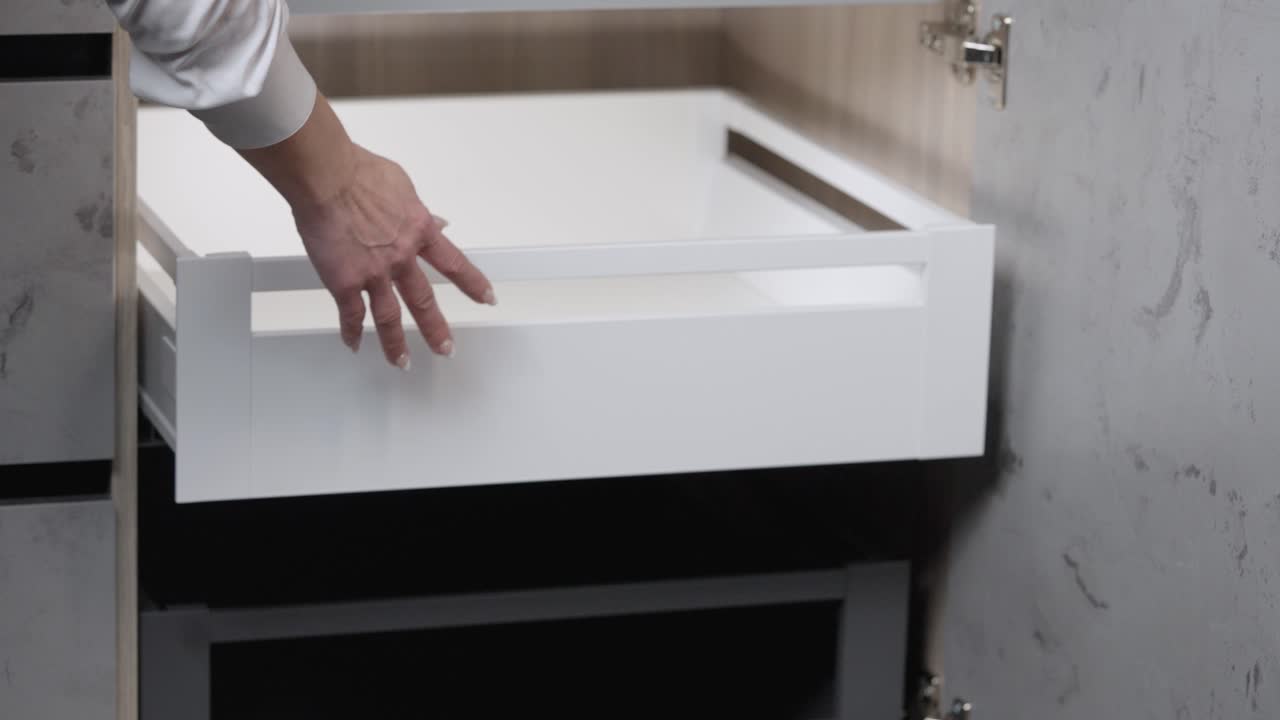 mujer con uñas pintadas abre y cierra el cajón del armario