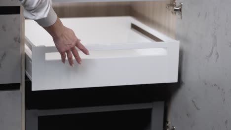 woman with painted fingernails opens and closes cabinet drawer