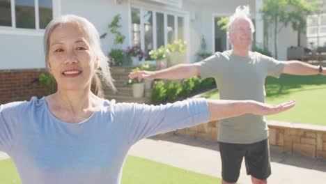 Happy-diverse-senior-couple-practicing-yoga-on-sunny-day-in-garden