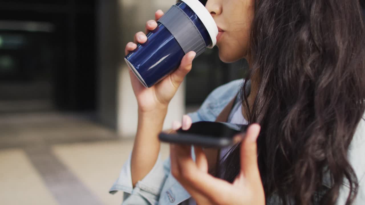 mujer asiática caminando hablando en el teléfono inteligente y bebiendo café para llevar