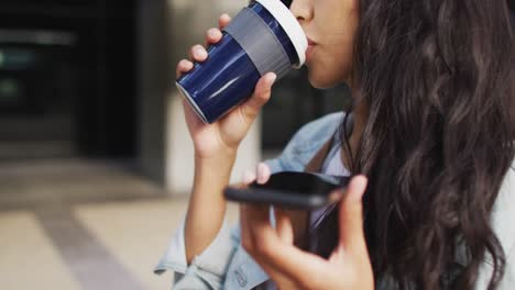 asian woman walking talking on smartphone and drinking takeaway coffee