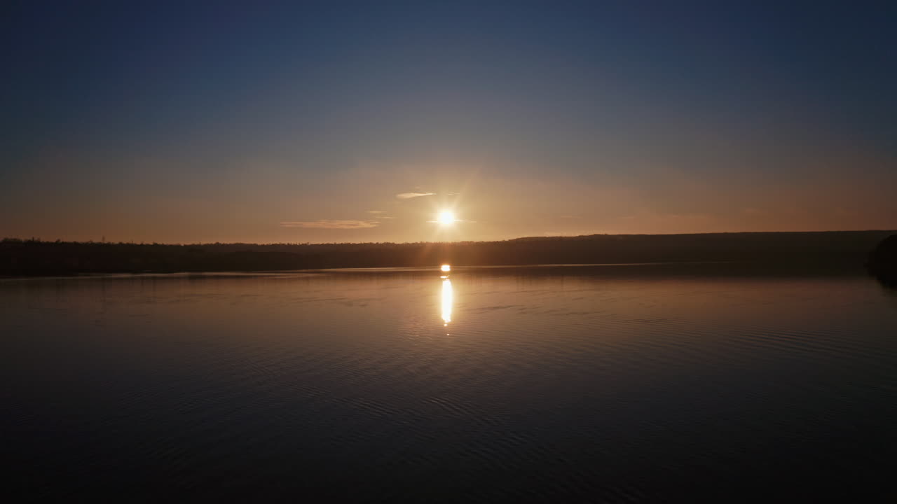 River at sunset. Setting sun reflects on the water surface in the evening. Beautiful view of the lake with setting sun on the evening sky.