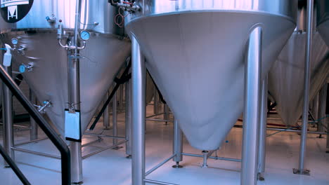 slow pan left of large stainless steel beer fermentation tanks in a brewery
