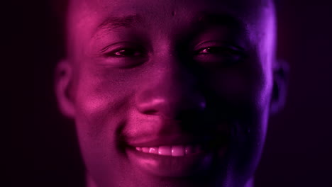 close-up portrait of a smiling man with vibrant purple and pink lighting