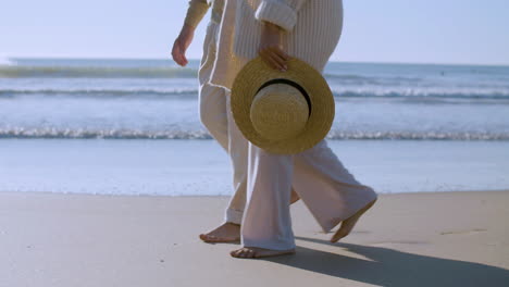 felice coppia caucasica senior che cammina e parla sulla spiaggia in una giornata di sole