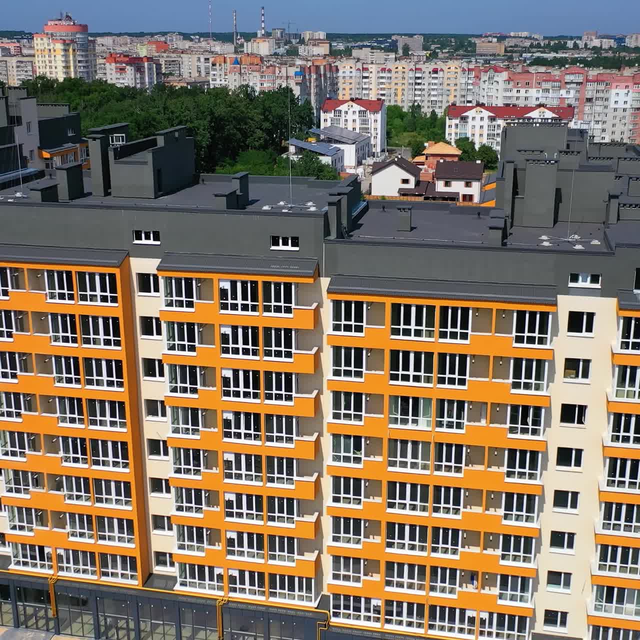 Exterior of modern architecture in the city. New apartment building with colorful walls and grey roof. Residential block of flats newly built. Aerial view