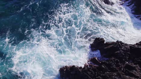 Toma-Ascendente-De-Drones-De-Poderosas-Olas-Cubiertas-De-Blanco-Del-Agua-Clara-Del-Pacífico-Chocando-Violentamente-Contra-El-Acantilado-Rocoso-En-La-Isla-De-Oahu,-Hawaii.