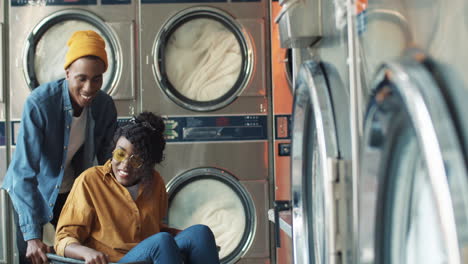 young cheerful couple having fun in laundry service room