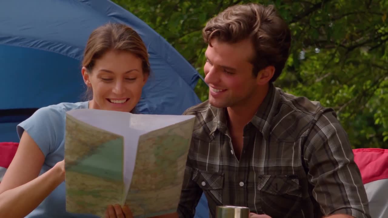 una pareja con un mapa sentada fuera de su tienda