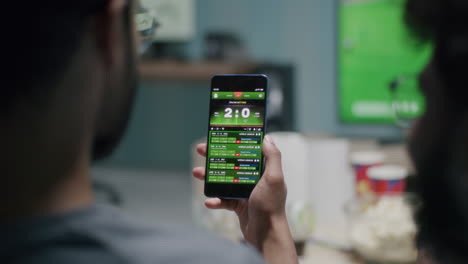 person engaging in online sports betting on a smartphone while watching a game