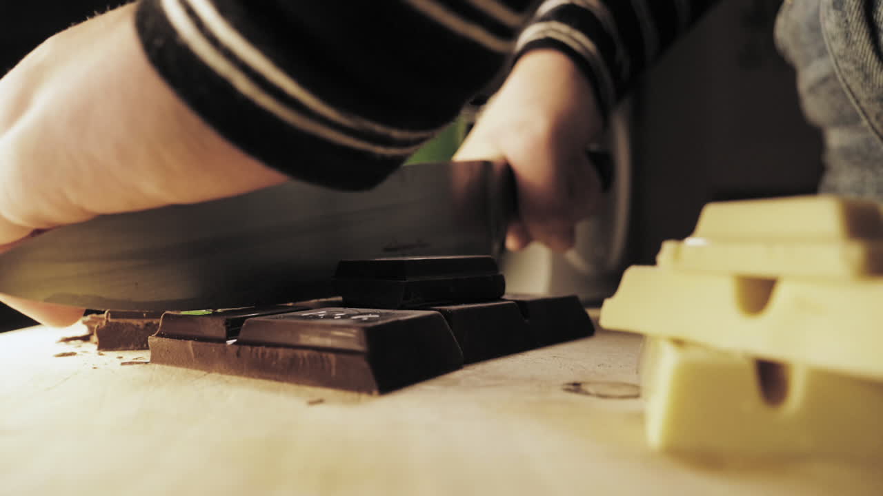 Slow Motion of female hands preparing chocolate cookies cutting up dark chocolate.