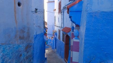 quaint steep alley with blue painted walls in touristic chefchaouen, morocco