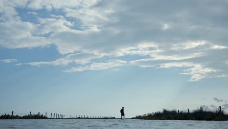 wide shot of male walking in flooded beach area