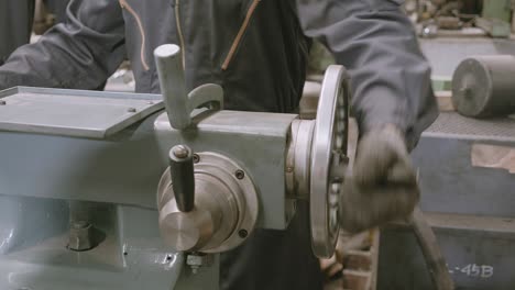 hand of engineer man operating using industrial machine in factory, male using skilled manual for control machinery with precision, technician and workman, metalworker and workshop and construction.