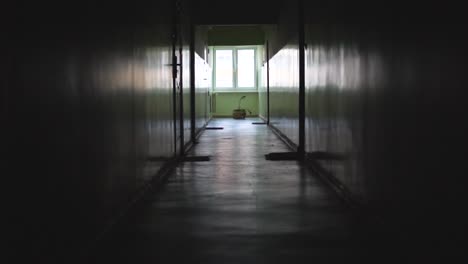 slow motion shot in an old dark empty corridor in a block of flats, a stylized place with a window at the end of the corridor, slowly walk forward