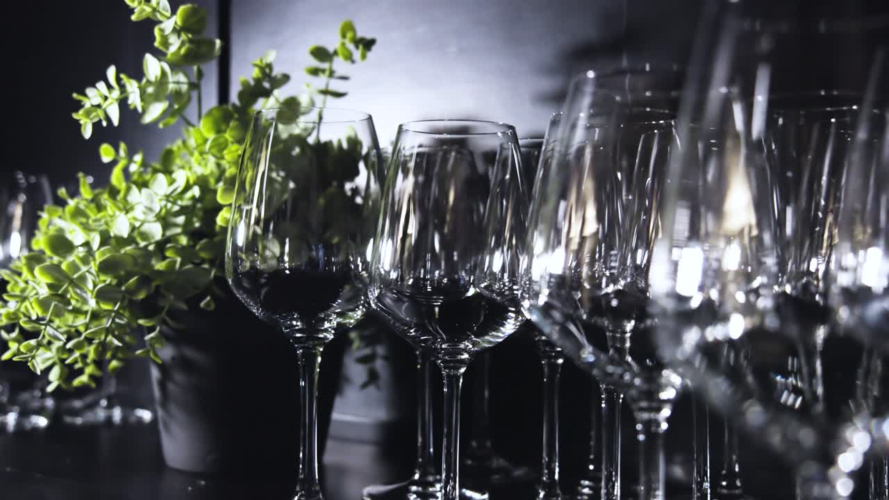 Nærbillede af mange vinglas placeret på begge sider af en indendørs plante inde i en restaurant