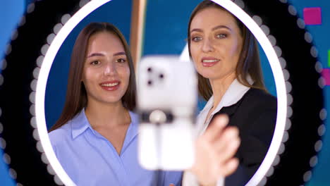 positive beautiful caucasian ladies behind the camera and ring light. streaming online concept.