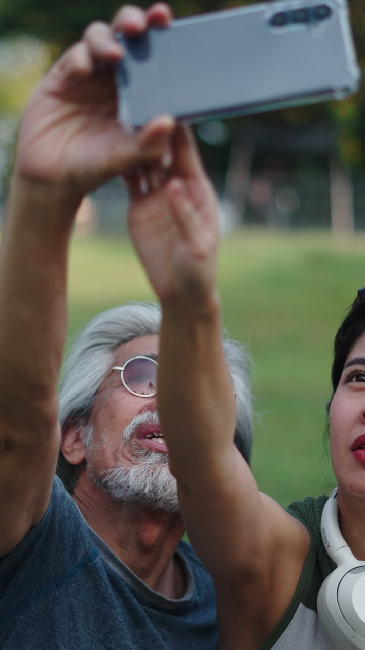 Happy Senior Man and Young Woman Taking Selfie in Park