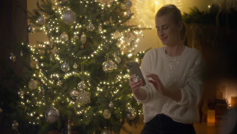 mujer tomando una selfie junto al árbol de navidad