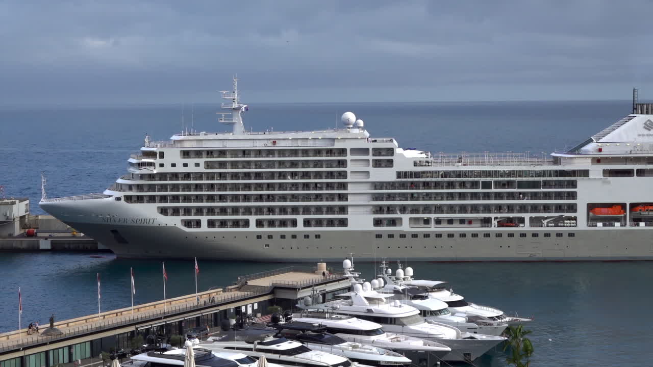 La Condamine, Monaco - July 4, 2025: Side view of a large cruise ship docked in Monaco, revealing multiple decks, balconies, and passengers enjoying ocean view