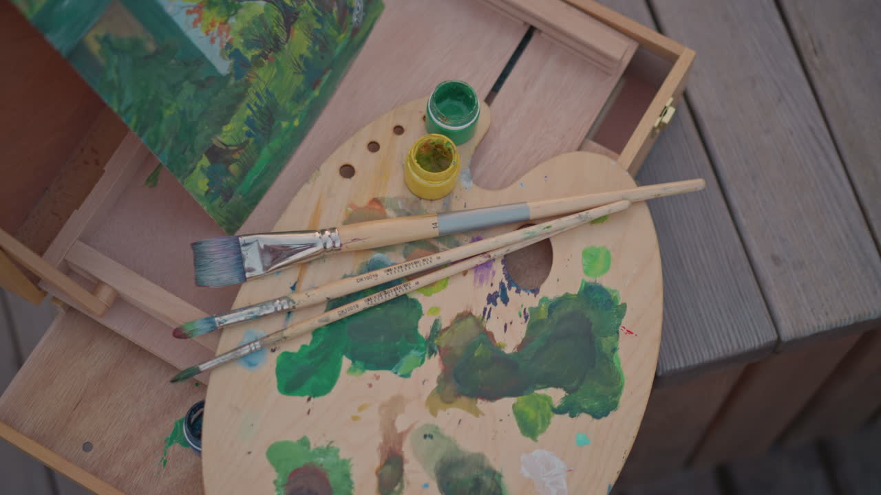 Strumenti artistici colorati su superficie in legno. Materiali creativi per la pittura con pigmenti vivaci e pennelli esposti. Vista ravvicinata di strumenti artistici e colori vividi disposti su sfondo in legno