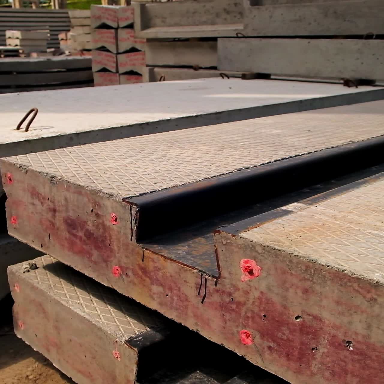 Massive concrete plate with metal rail inside. Close up. Multiple cement materials stacked at background