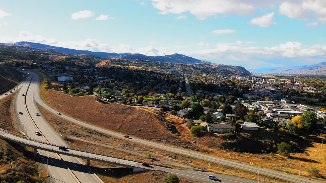 캐나다 bc 주 캠룹스의 고속도로 1번 오른쪽 정상 속도 팬 샷, 자동차와 트럭 운전, 흐린 날 사막 환경의 배경에 있는 도시