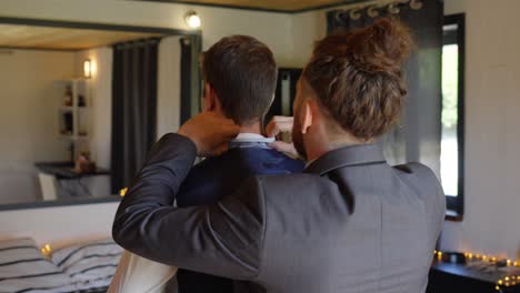 slow motion shot of a best man helping the groom with his suit and tie