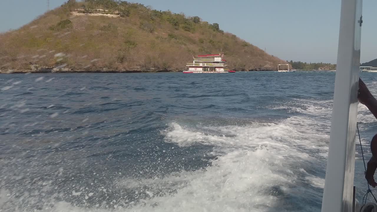 Bali Indonesia seen from fast moving boat and big ocean waves and other boats in frame.