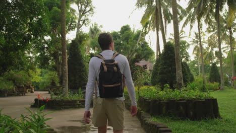 man walking through a tropical garden