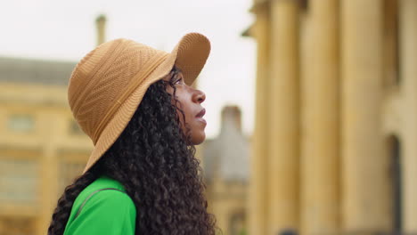 female tourist wearing straw sun hat with camera on vacation in oxford uk exploring city walking along broad street taking photos of the sheldonian theatre