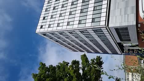 vertical glass front modern downtown college office building reflecting cloudy blue sky