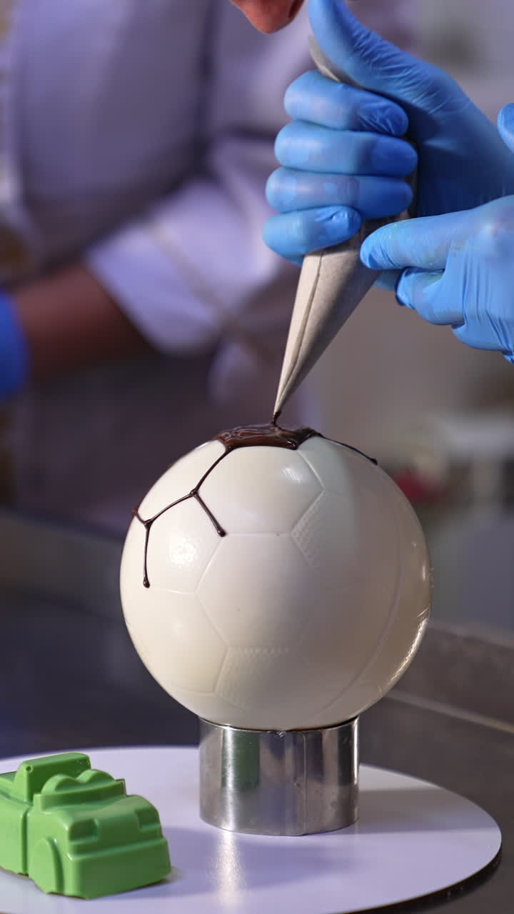 Confectioners decorating cakes in the confectionary. Two cooks working with sweets at the metal table. Blurred backdrop. Vertical video