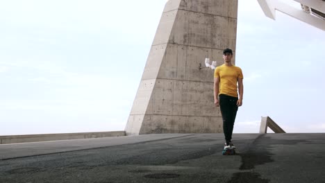 Young-Attractive-Trendy-Man-skateboarding-fast-under-a-solar-panel-on-a-morning-sunny-day-with-an-urban-city-background-in-slow-motion