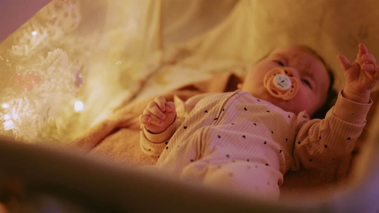 Primo piano di un bambino con un ciuccio illuminato da calde luci natalizie, che crea un’atmosfera festosa e toccante