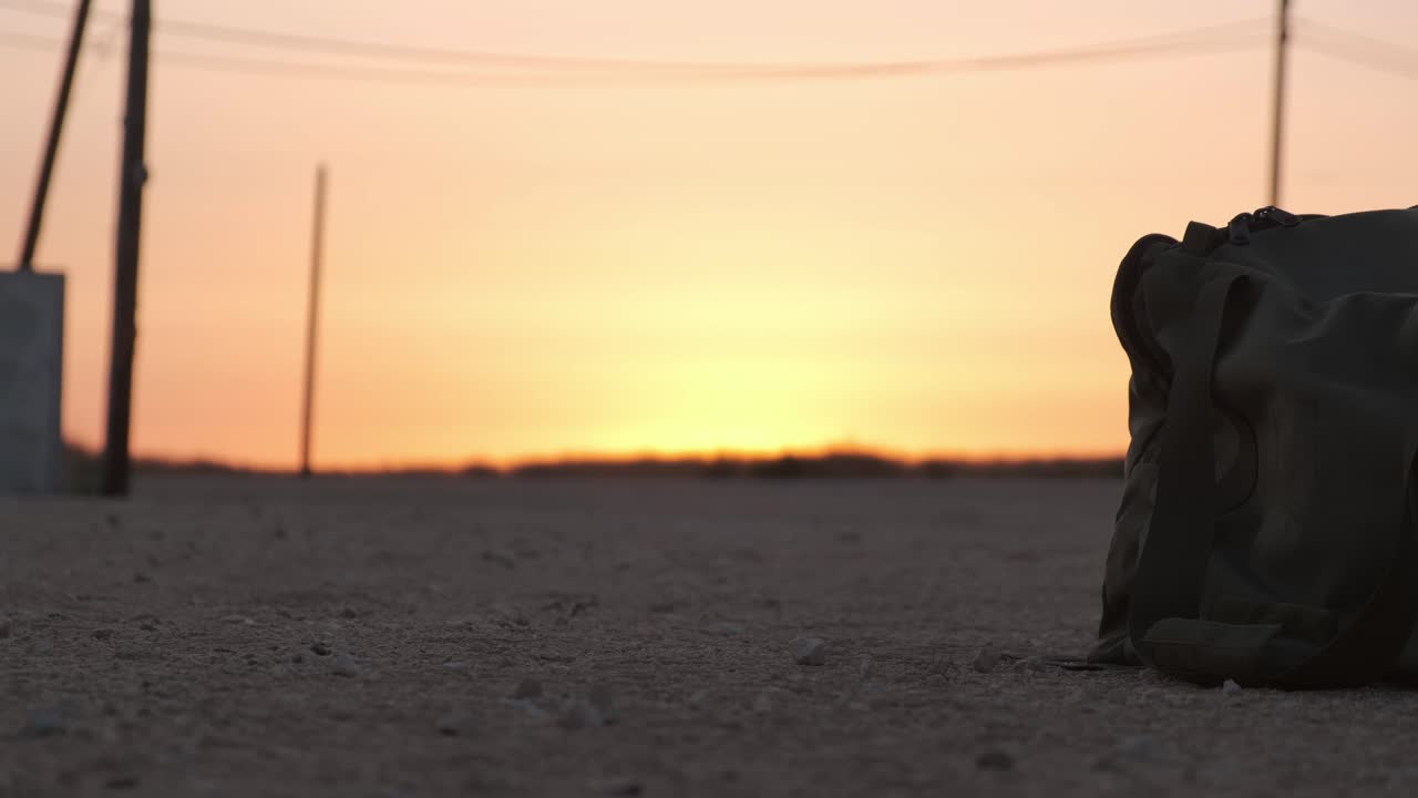 Close-up de mochila militar no chão no deserto ao pôr do sol