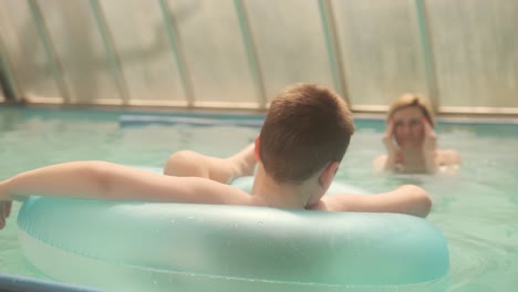 Happy Family Mom and Little Son in a Circle Swim in the Pool with Blue Water at the Hotel.
