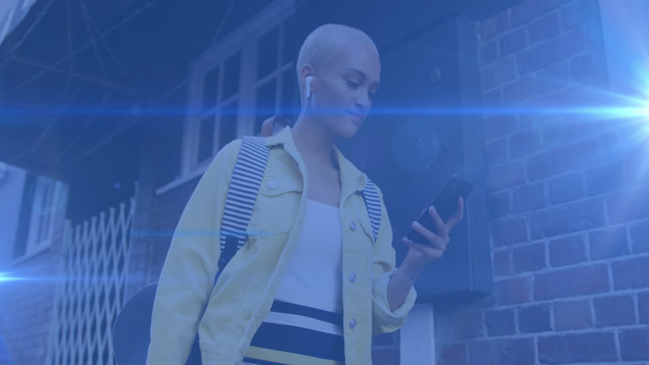 Video di luci colorate su una donna di etnia mista che va al lavoro, usando lo smartphone per strada.