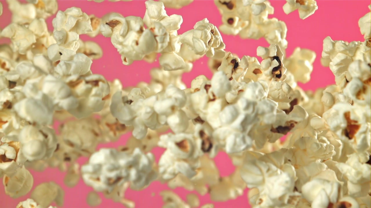 Popcorn che volano e cadono al rallentatore su sfondo rosa