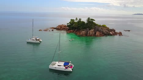 two sailboats anchor in front of tropical st