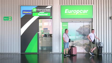 two men waiting at airport car rental counters