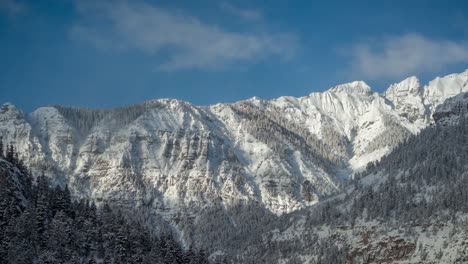 timelapse, snow capped mountains and light clouds in idyllic winter landscape on sunny day