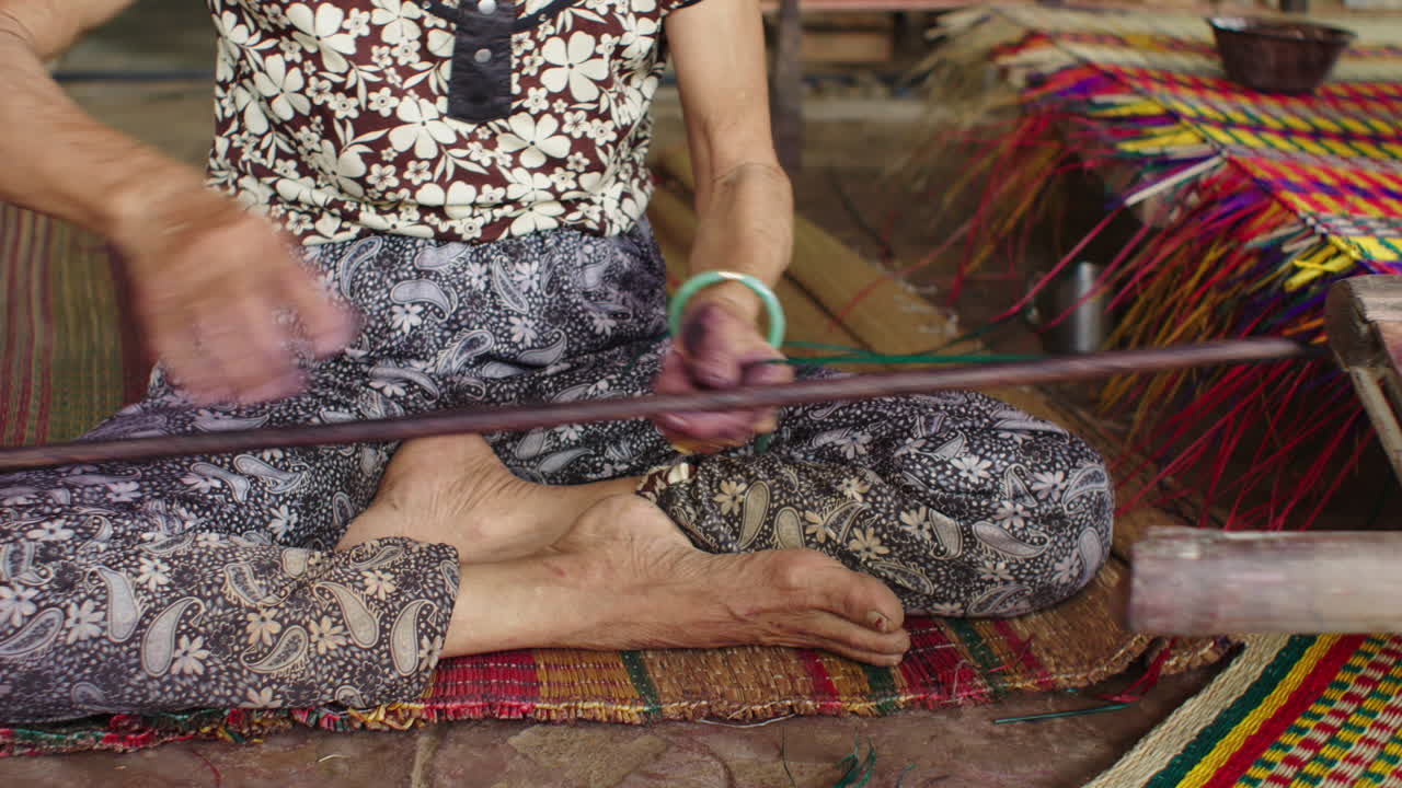 Close up shot of hands of a senior female making traditional mattress in Quang Nam province, Vietnam inside a small handloom